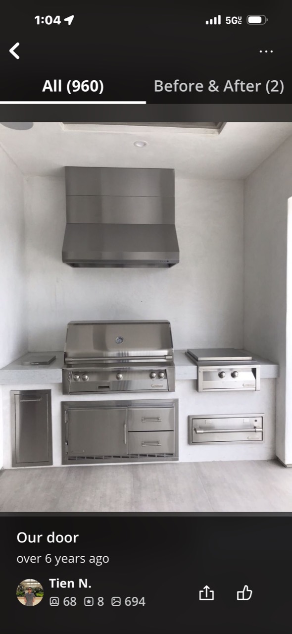 Stainless outdoor kitchen with barbecue grill, ventilation hood, side burner, and storage
